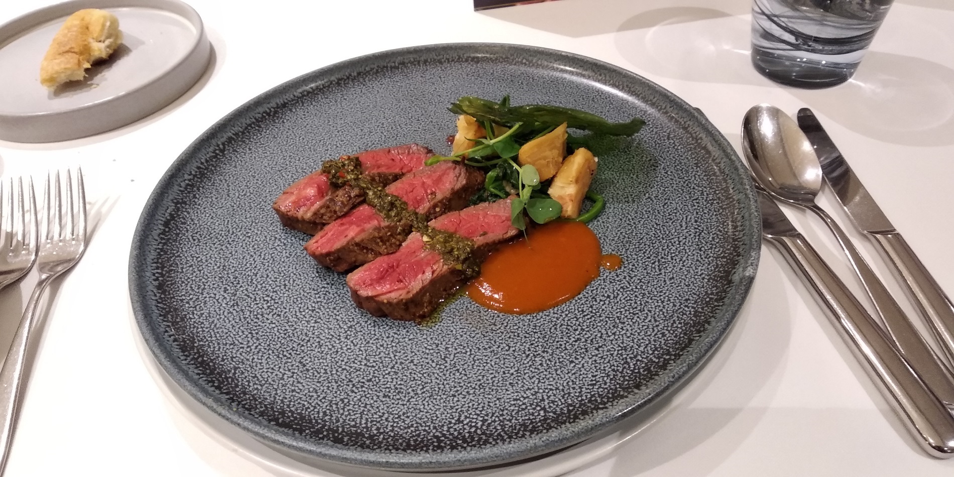 Seared pommery & rosemary wagyu flank 7+, wilted spinach & garlic, honey roasted red pepper coulis, chimichurri, micro coriander. (Fajar Sidik/Hypeabis.id)