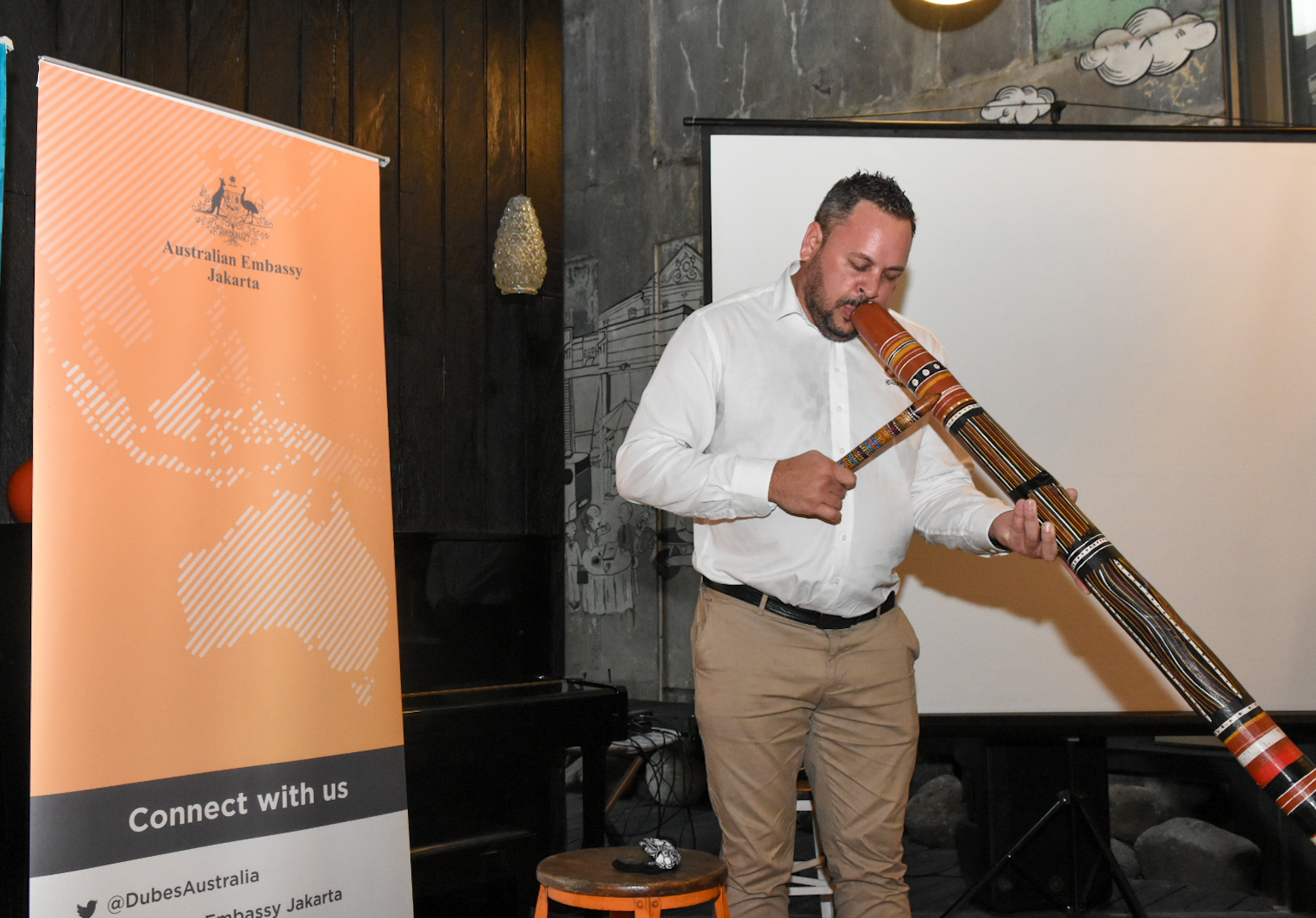 Direktur Eksekutif Gilimbaa David Williams bermain alat musik Digderidoo dalam acara Creative Talks National Aborigines and Islanders Day Observance Commitee 2022, Selasa (5/7/2022). (Sumber gambar: Kedutaan Besar Australia Jakarta)