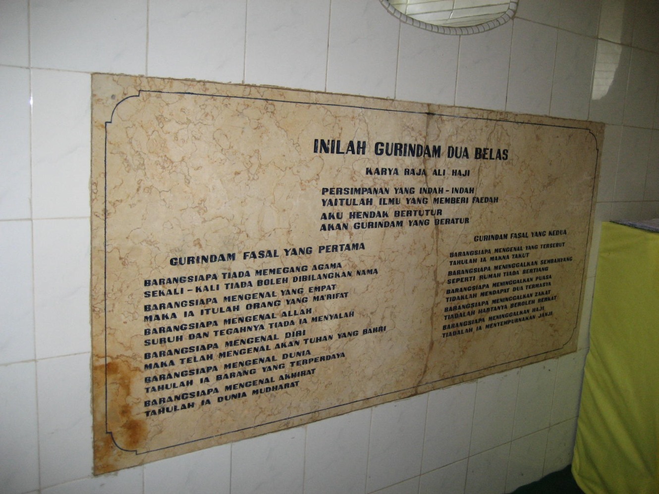 Gurindam 12 pasal pertama dan kedua yang di dinding makam Engku Puteri Hamidah di Pulau Penyengat, Kepulauan Riau. (Sumber gambar: Wikimedia Commons)