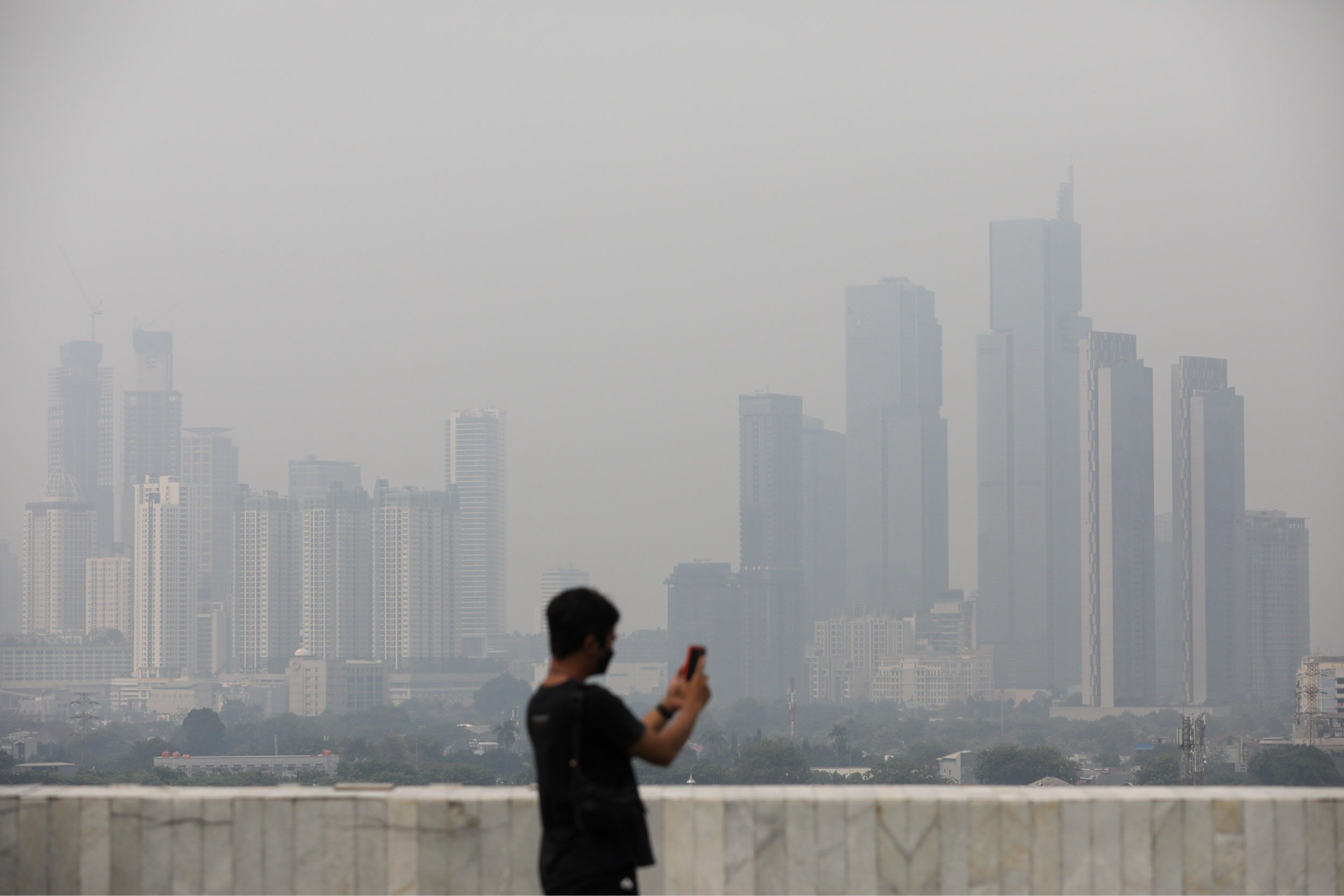 Warga mengambil foto gedung bertingkat yang diselimuti kabut tebal di Jakarta, Kamis (31/8/2023).  Arief Hermawan P