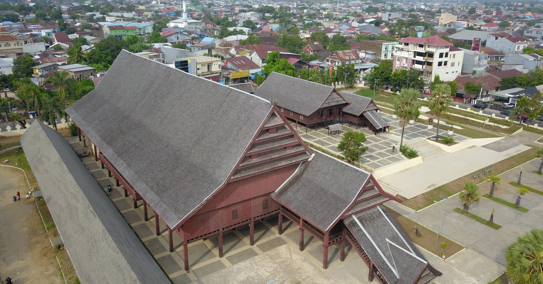 Pengunjung di depan Rumah panggung Balla Lompoa. (Sumber gambar: Unsplash/Andi Hasbi Jaya)