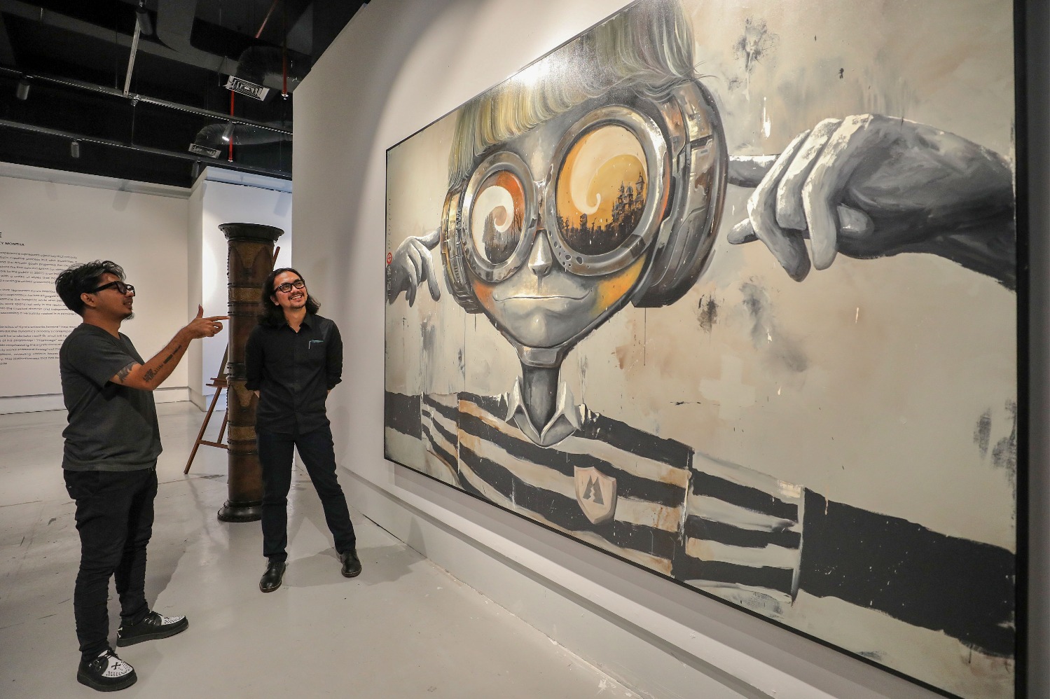 Kurator Bob Edrian (kanan) berbincang dengan Seniman Oky Rey Montha (kiri) di depan karya bertajuk Metal Shield. (Sumber gambar: JIBI/Bisnis/Eusebio Chrysnamurti)