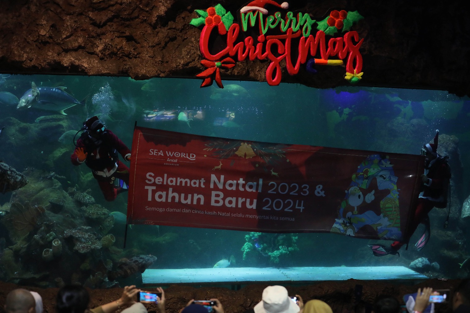 Penyelam berpakaian Santa Claus menghibur pengunjung di akuarium Sea World Ancol, Jakarta, Senin (25/12/2023). 