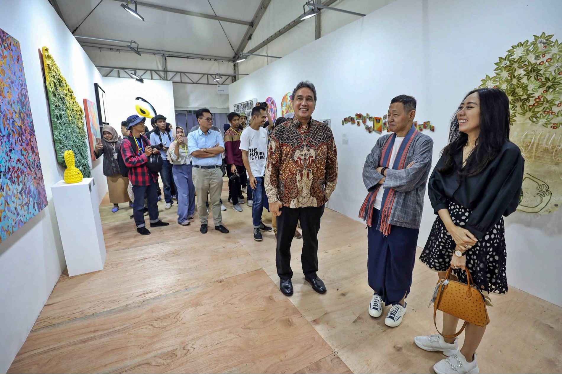 Pengunjung mengamati karya seni yang dipamerkan di Art Jakarta Gardens di Hutan Kota by Plataran, Jakarta, Selasa (23/4/2024). (Hypeabis.id/Arief Hermawan P)
