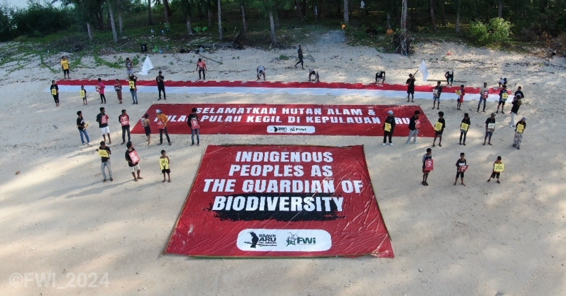  Pemuda adat Aru melakukan aksi damai seraya membentangkan spanduk (Sumber gambar: Forest Watch Indonesia) 