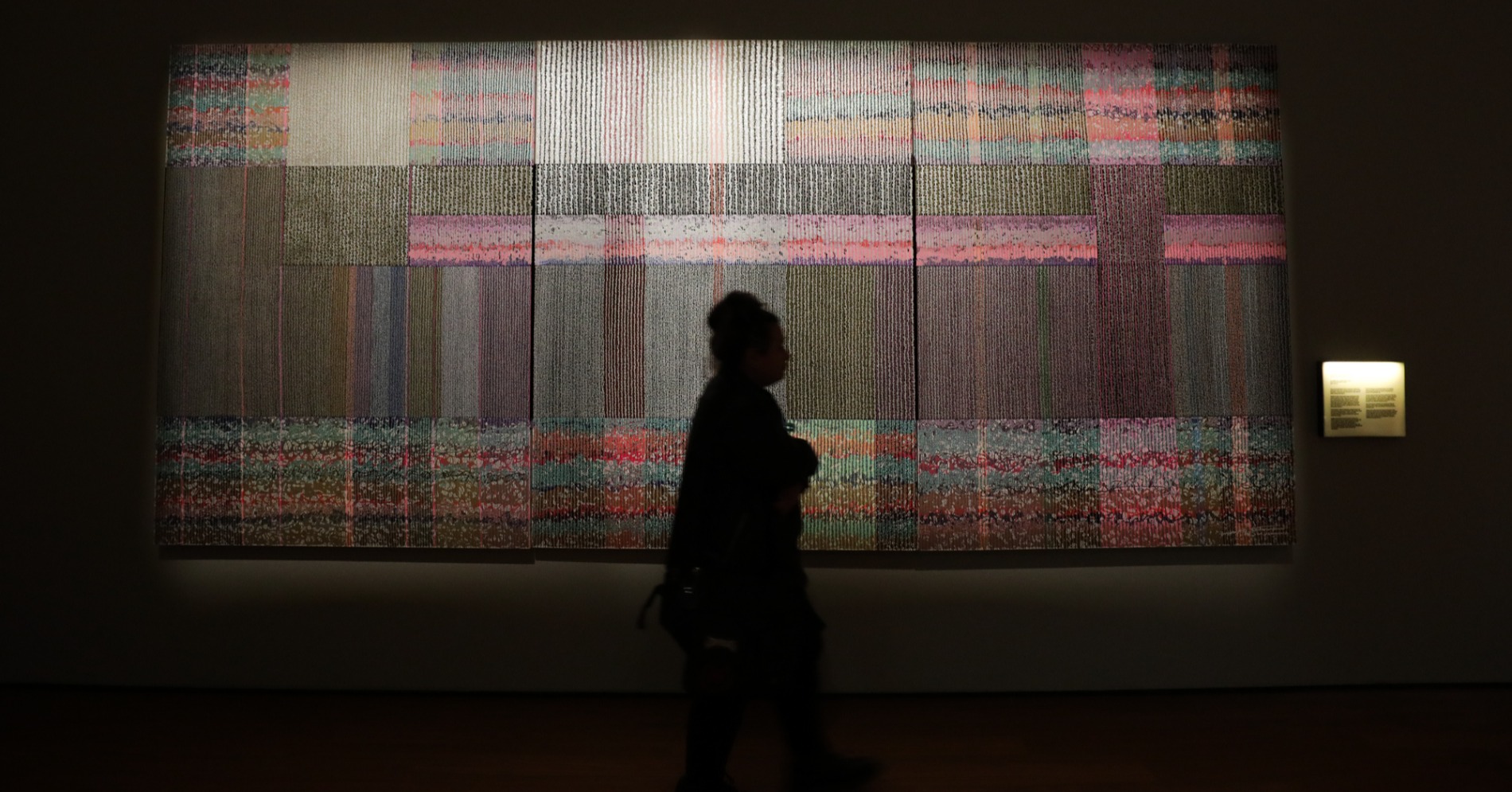 Pengunjung melintasi karya bertajuk Vibrasi Bara Tanah Nusantara dalam pameran Nyala: 200 Tahun Perang Diponegoro, di Galeri Nasional Indonesia, Senin, (21/7/25). (sumber gambar: Hypeabis.id/Fanny Kusumawardhani)