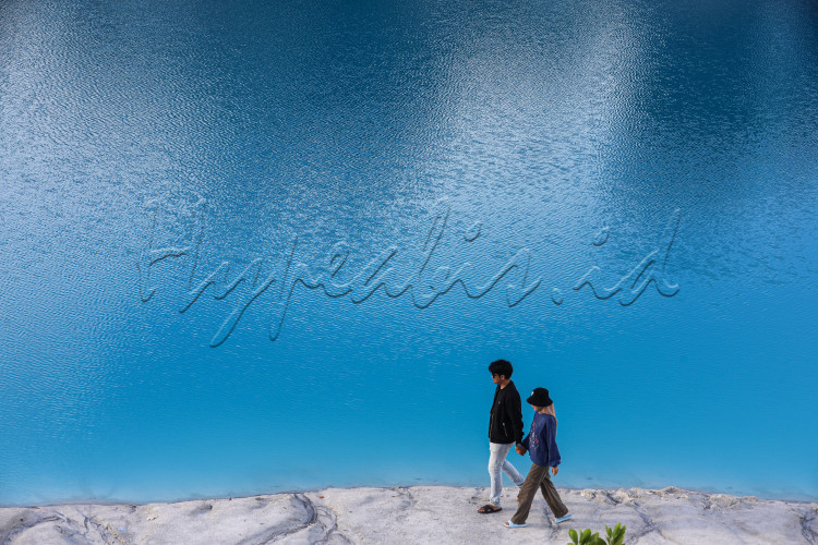 Pasangan muda-mudi berjalan dikawasan wisata Danau Kaolin. Danau Kaolin menjadi sebutan beberapa galian pertambangan di Pulau Bangka dan Pulau Belitung. Galian tersebut sudah ditinggalkan sejak 1971. Airnya menjadi warna biru dan indah dilihat, Selasa (27/7/2023)