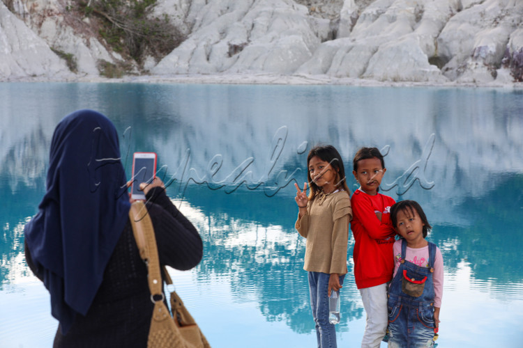 Pengunjung berfoto dengan latar danau Kaolin. Danau Kaolin menjadi sebutan beberapa galian pertambangan di Pulau Bangka dan Pulau Belitung. Galian tersebut sudah ditinggalkan sejak 1971. Airnya menjadi warna biru dan indah dilihat, Selasa (27/7/2023)