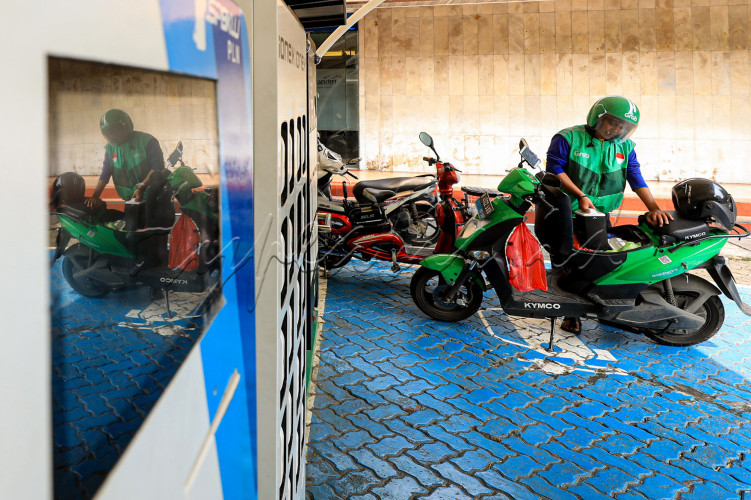 Driver ojek online menukar baterai motor listrik di SPKLU PLN, Jakarta.