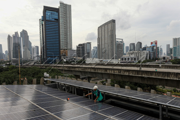 Teknisi membersihkan panel surya di salah satu perkantoran di Jakarta.