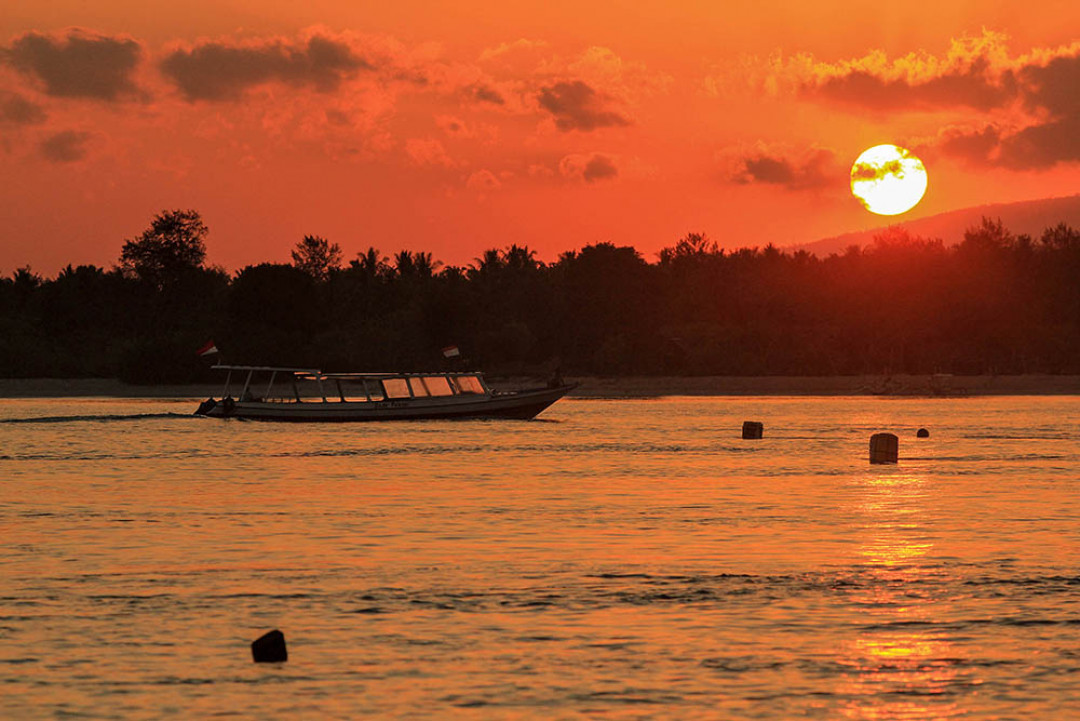 Matahari terbit di Gili Trawangan, Lombok, Nusa Tenggara Barat. Pulau seluas 340 ha ini merupakan pulau terbesar sekaligus pulau teramai dibanding dua pulau lainnya, yakni Gili Meno dan Gili Air. Pasir putih serta laut biru menjadi andalan bagi ketiga pulau yang terletak di utara Pulau Lombok ini. Beragam aktivitas bisa dilakukan di Gili Trawangan, mulai dari berjemur, snorkeling dan diving.