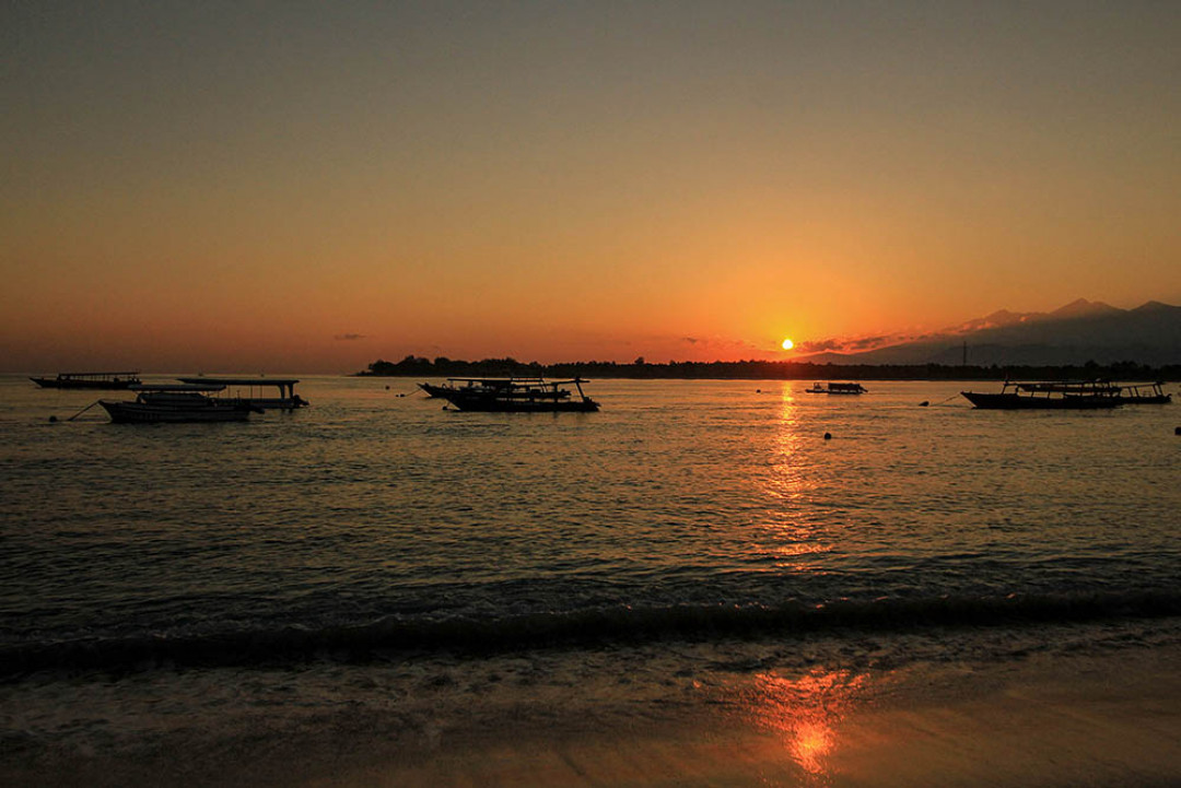 Matahari terbit di Gili Trawangan, Lombok, Nusa Tenggara Barat. Pulau seluas 340 ha ini merupakan pulau terbesar sekaligus pulau teramai dibanding dua pulau lainnya, yakni Gili Meno dan Gili Air. Pasir putih serta laut biru menjadi andalan bagi ketiga pulau yang terletak di utara Pulau Lombok ini. Beragam aktivitas bisa dilakukan di Gili Trawangan, mulai dari berjemur, snorkeling dan diving.