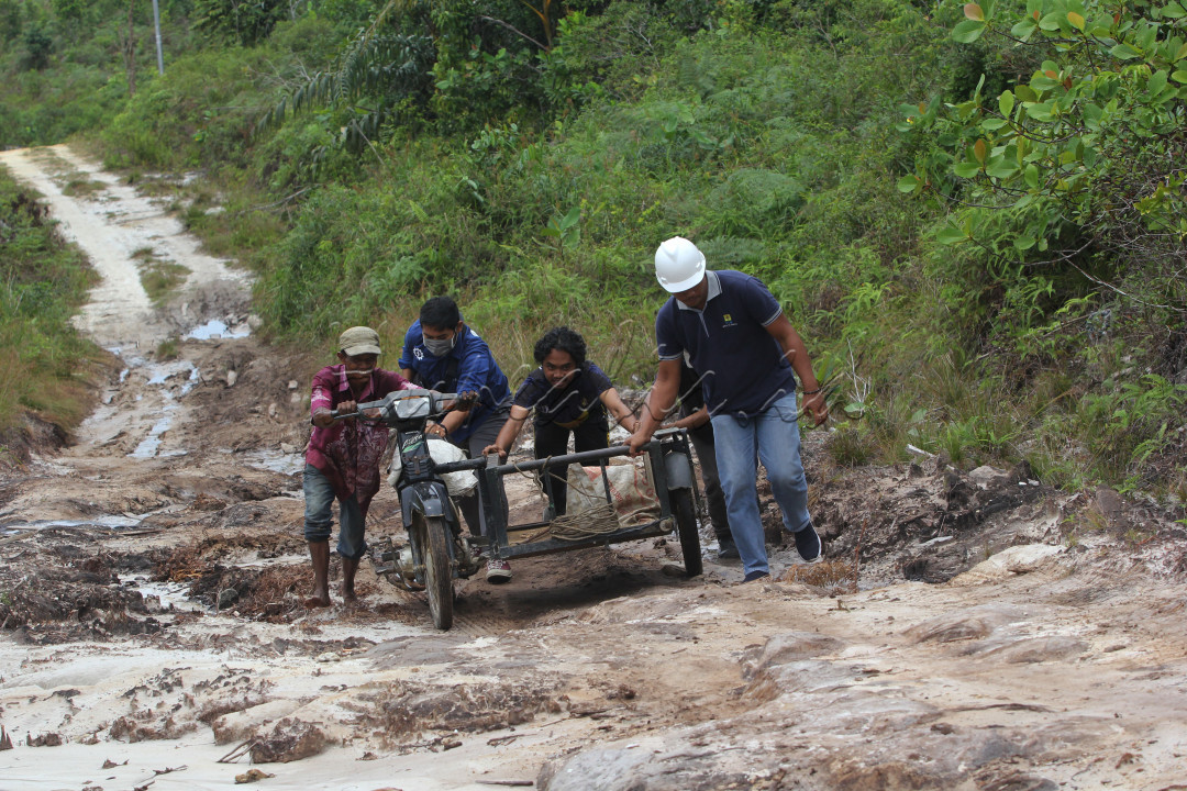 Warga saling tolong menolong becak motor yang kesulitan jalan di jalan yang belum jadi di desa segaram Kabupaten Natuna, 25 Septemebr 2020.