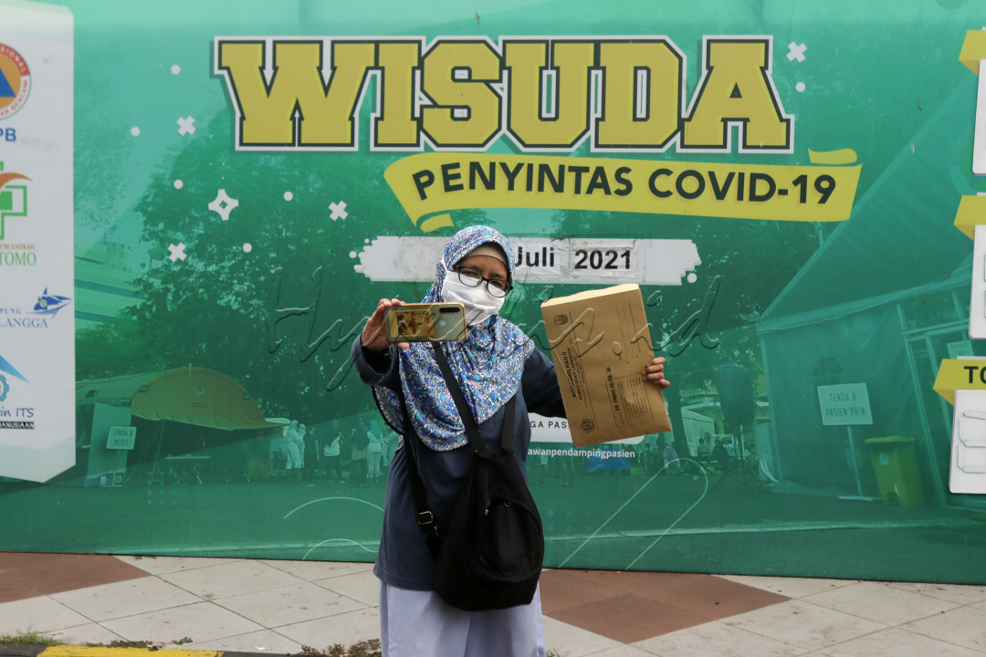 Seorang pasien COVID-19 yang dinyatakan sembuh, berswa foto dengan latar belakang Wisuda Penyintas COVID-19 di RS Lapangan Indrapura Surabaya, Jumat (9/7). Pada Jumat kemarin RS Lapangan memulangkan sebanyak 100 pasien sembuh, yang merupakan terbanyak pada satu hari.&nbsp;