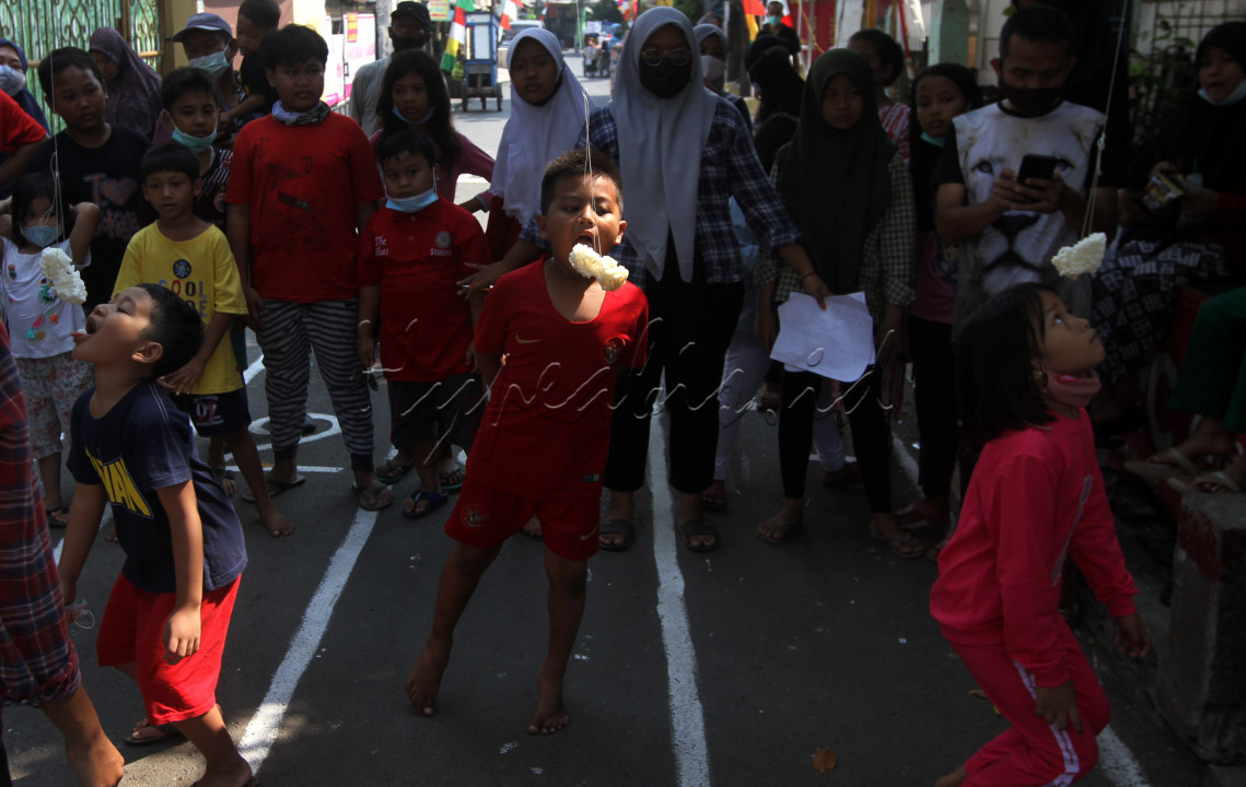 Sejumlah anak mengikuti lomba makan kerupuk ditengah pengetatan PPKM di Jakarta, Selasa (17/8). Walaupun pada masa pandemi sejumlah masyarakat tetap memeriahkan hari kemerdekaan ke-76 RI dengan perlombaan.