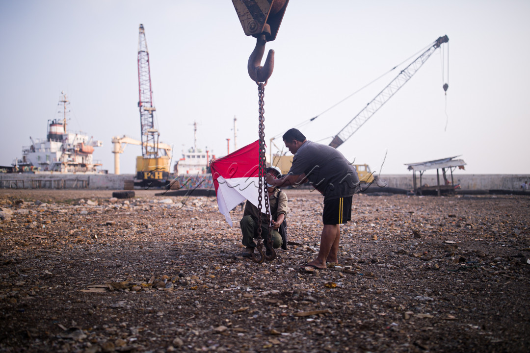 Warga memasang Bendera Merah Putih di di alat berat crane saat peringatan HUT ke-76 Republik Indonesia di Belah Kapal, Cilincing, Jakarta Utara, Selasa (17/8/2021).