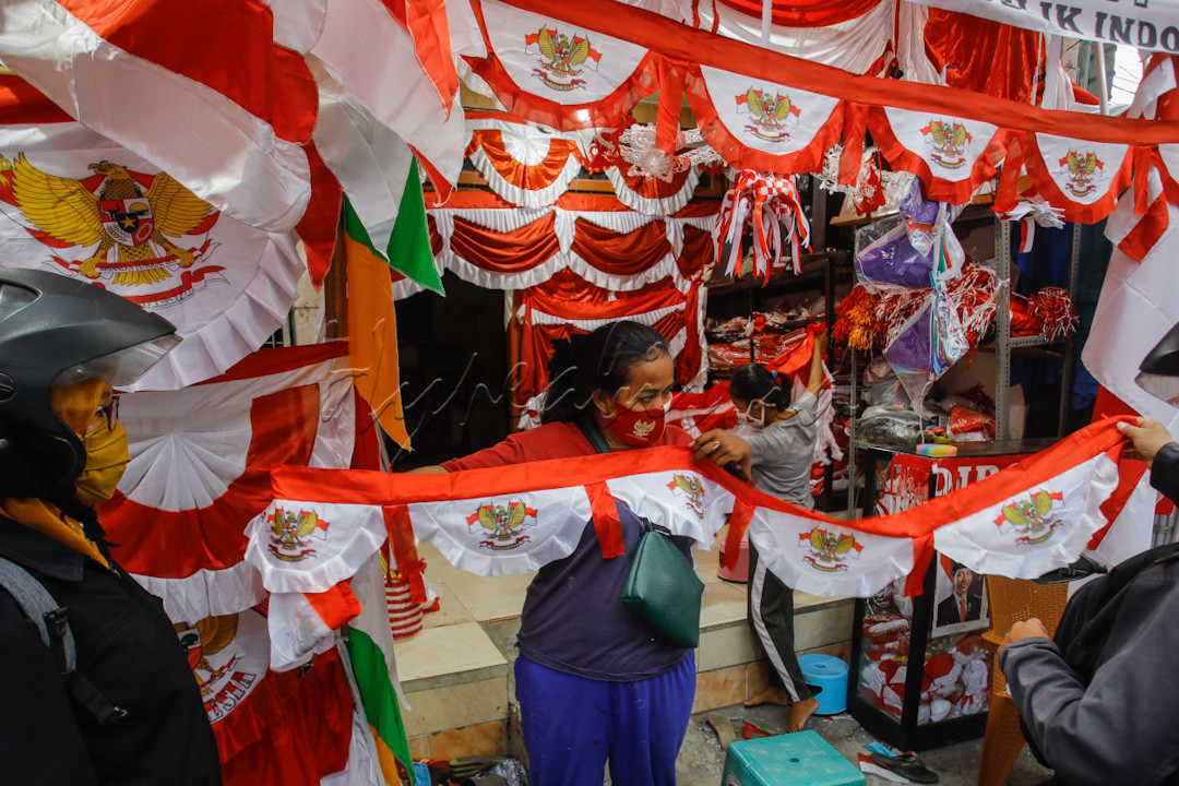 Sejumlah pedagang bendera mempersiapkan pesanan bendera dari pelanggan untuk hiasan kantor dalam rangka memperingati HUT RI ke 76 dijalan Darmokali Surabaya. Penjualan hiasan bendera merah putih memasuki tahun kedua ditengah pandemi Covid-19 mengalami sedikit peningkatan jika dibandingakan dengan tahun 2020 awal pandemi, perihal ini disebabkan aturan Pemerintah Kota dengan adanya PPKM (Pemberlakuan Pembatasan Kegiatan Masyarakat) membatasi gerak penjual dan pembeli dari luar kota untuk memesan bendera. Selain itu, harga yang ditawarkan juga tetap tidak mengalami perubahan mulai dari Rp 5000 hingga Rp 600.000 bahkan lebih tergantung dari besar ukurannya.