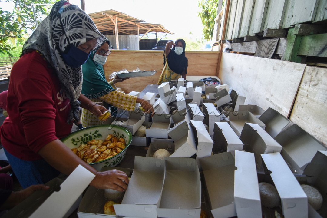 Sejumlah ibu-ibu menyiapkan nasi bungkus untuk warga yang menjalani isolasi mandiri akibat terjangkit Covid-19 di sebuah dapur umum di Dusun 01 Desa Langaleso, Kecamatan Dolo Kabupaten Sigi, Sulawesi Tengah. Dapur umum dengan nama "warga bantu warga" dibuat secara sukarela oleh masyarakat di daerah setempat akibat banyak warga yang menjalani isolasi mandiri. Di dapur umum itu belasan ibu-ibu bergotong royong menyediakan ratusan nasi bungkus untuk warga isoman.&nbsp;
