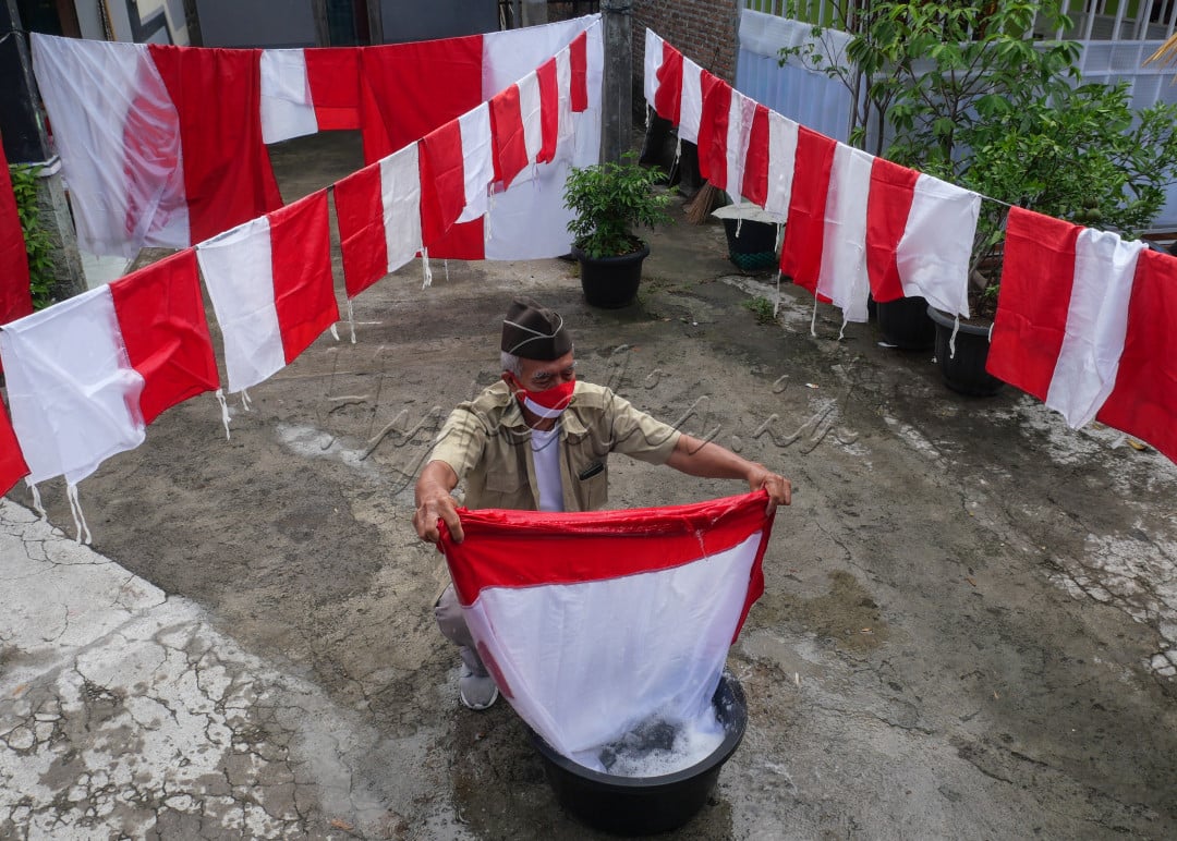 Menyambut perayaan 17 Agustus, seorang warga mencuci bendera halaman rumah.&nbsp;