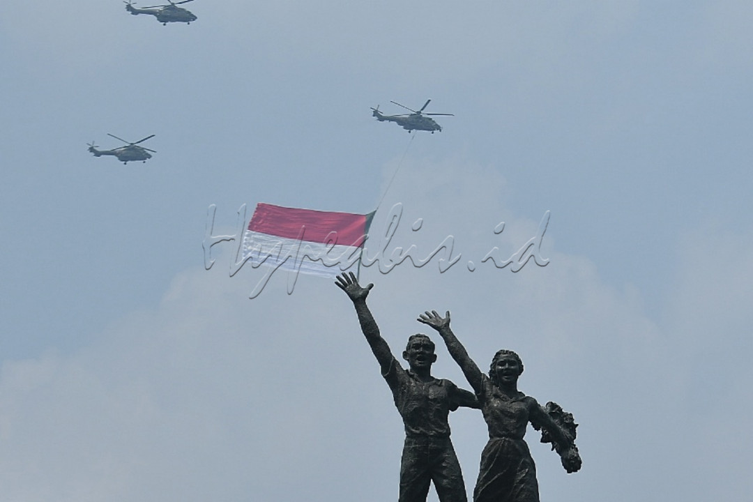 Sejumlah helikopter TNI Angkatan Udara mengibarkan bendera merah putih raksasa di langit Jakarta saat Upacara Peringatan Detik-Detik Proklamasi di Bundaran HI, Jakarta, Selasa (17/8/2021). Pengibaran bendera merah putih raksasa yang berukuran 20 x 30 meter tersebut dalam rangka memperingati HUT ke-76&nbsp;Republik Indonesia.