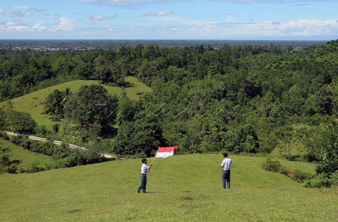 Dua siswa SMAN 1 Masamba, Luwu Utara mengibarkan bendera Merah Putih di di Bukit Teletubies di Desa Kamiri, Luwu Utara, Sulsel, 17 Agustus 2021.&nbsp;