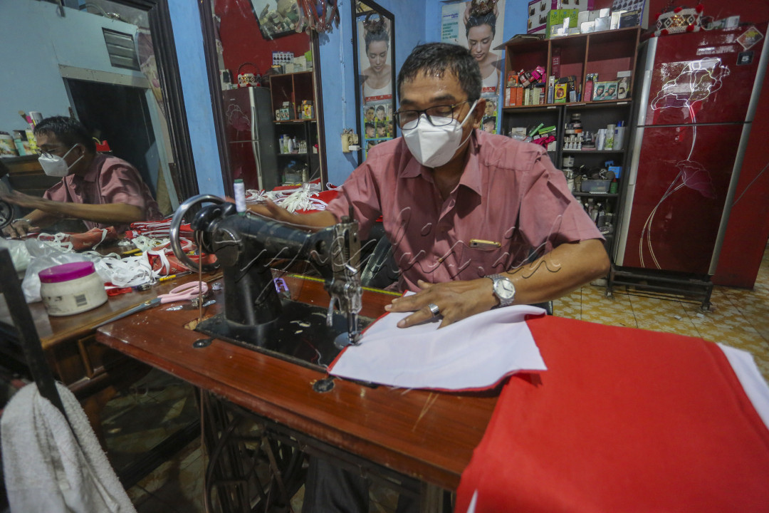 Seorang Bapak sedang menjahit Bendera Merah Putih&nbsp; dijual untuk pengahasil tambahan , di massa PPKM saat ini menjual bendera Merah Putih saat merayakan hari Kemerdekaan Republik Indonesia moment yang baik untuk menambah penghasilan buat keluarga.
