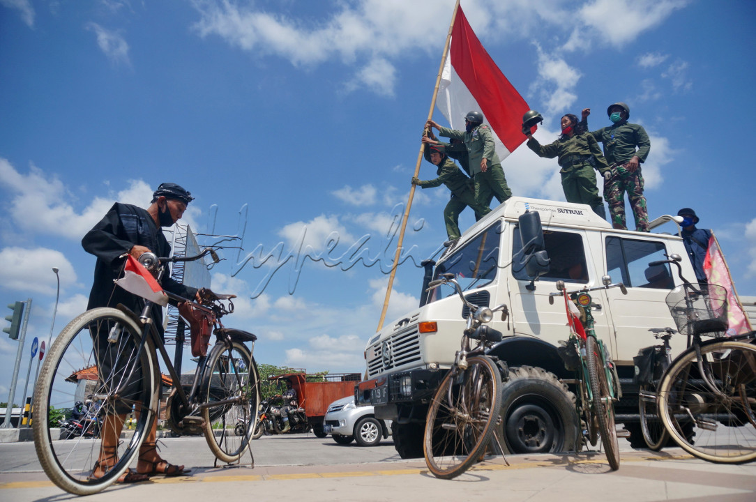 Dengan berpakaian ala pejuang, para anggota dari komunitas sepeda kuno ini berusaha menegakkan bendera disebuah truk.&nbsp;