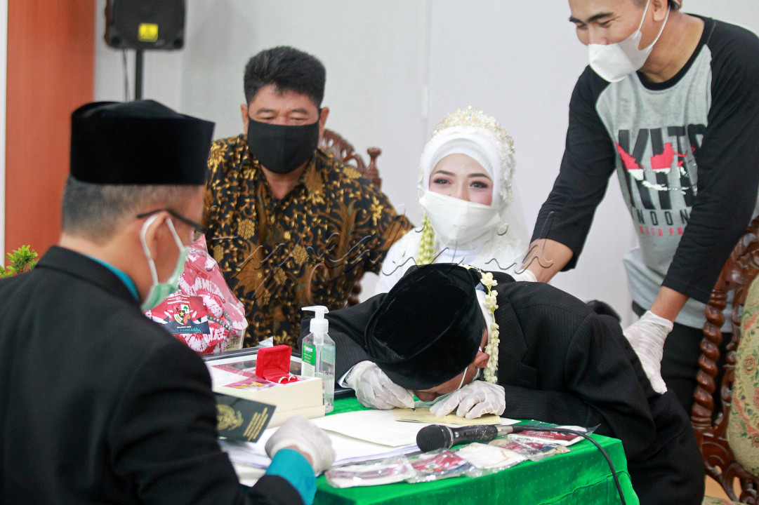 Mujiono, penyandang low vision menandatangani buku nikah disaksikan istrinya Dewi Susilowati, penyandang tunadaksa, saat mengikuti acara Nikah Gratis di KUA Sewon, Bantul, Selasa (8/6/2021). Nikah Bareng Gratis yang digelar oleh Forum Ta'aruf Indonesia tersebut diikuti lima pasang pengantin dan bertujuan untuk meringankan biaya pernikahan dalam masa pandemi Covid-19, seperti cincin, mahar, rias dan busana pengantin.&nbsp;