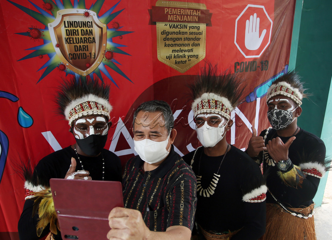Anggota TNI Angkatan Darat (AD) Bintara Otonomi Khusus asal Papua dengan menggunakan pakian adat berswa foto dengan warga usai mengikuti vaksinasi COVID-19 di Koramil Serpong, Serpong, Tangerang Selatan, Banten, Kamis (19/8/2021).&nbsp;Kehadiran Bintara Otonomi Khusus asal Papua tersebut menjadi daya tarik sendiri bagi warga sekitar untuk mengikuti Vaksinasi COVID-19 dosis pertama.&nbsp;
