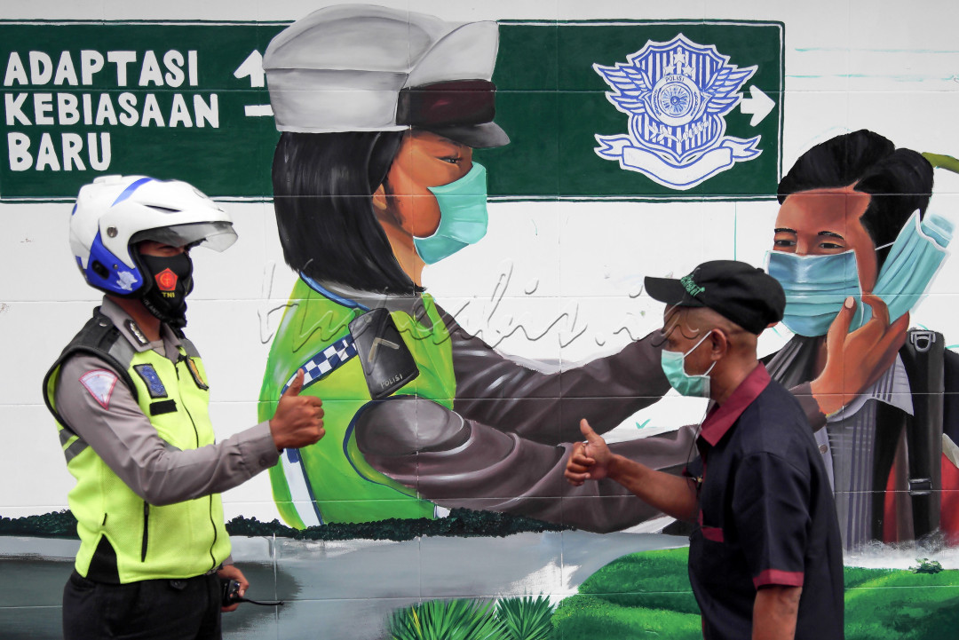 Aparat Polri memberikan isyarat ekspresi pujian dengan mangacungkan jempol tangan kepada warga masyarakat yang taat prokes dengan mengenakan masker saat beraktivitas diluar rumah di kota Medan, Sumatera Utara.