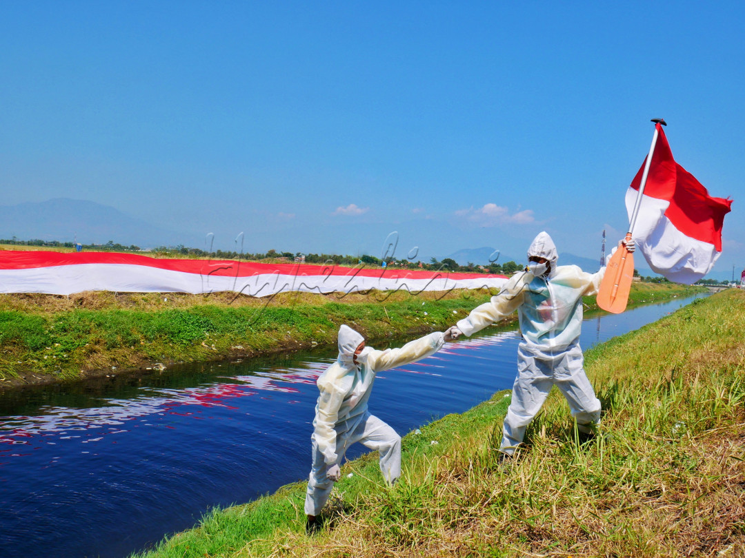 Seorang petugas tenaga kesehatan membantu temannya setelah melakukan kegiatan upacara 27 Agustus di bantaran sungai Cikijing, Rancaekek Kabupaten Bandung.&nbsp;