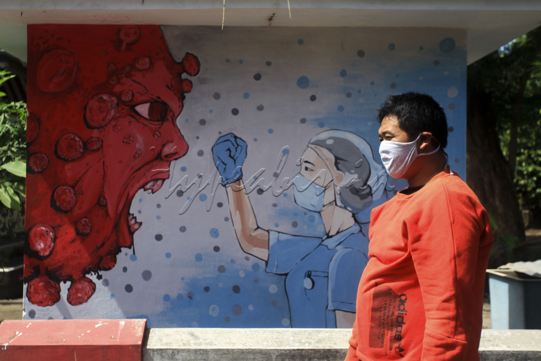 Warga melintas di dekat mural bergambar tenaga medis dan Virus Corona di kawasan Bantul, D.I Yogyakarta, Selasa (23/6/2020). Mural yang dibuat oleh warga itu guna mengingatkan warga agar waspada terhadap COVID-19 serta bertujuan bertujuan untuk memberikan dukungan atas perjuangan tenaga medis yang menjadi garis terdepan dalam penanganan COVID-19. <!--/data/user/0/com.samsung.android.app.notes/files/share/clipdata_210822_235607_853.sdoc-->