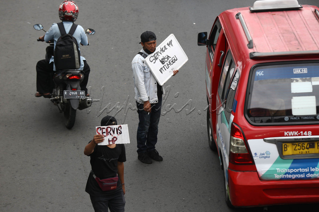 Tukang servis telepon seluler menawarkan jasanya di pinggir jalan Mayjen Sutoyo, Cililitan, Jakarta Timur, Selasa (13/7/2021). Para tukang servis telepon seluler terpaksa turun ke jalan menawarkan jasa mereka karena toko mereka di dalam mall harus ditutup pada masa PPKM level 4.<br />
&nbsp;