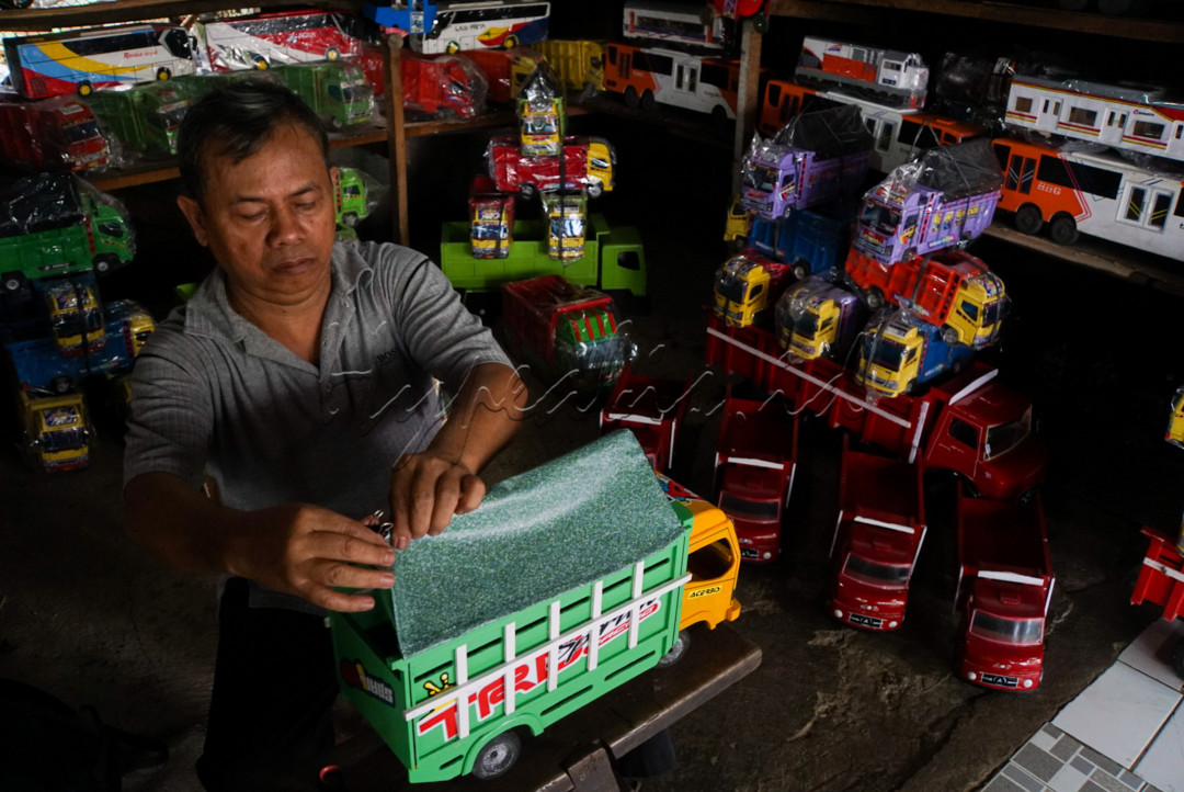 Pedagang mainan menyelesaikan pembuatan replika Truk Oleng yang ia jual di Jalan Raya Pasar Minggu, Jakarta Selatan.