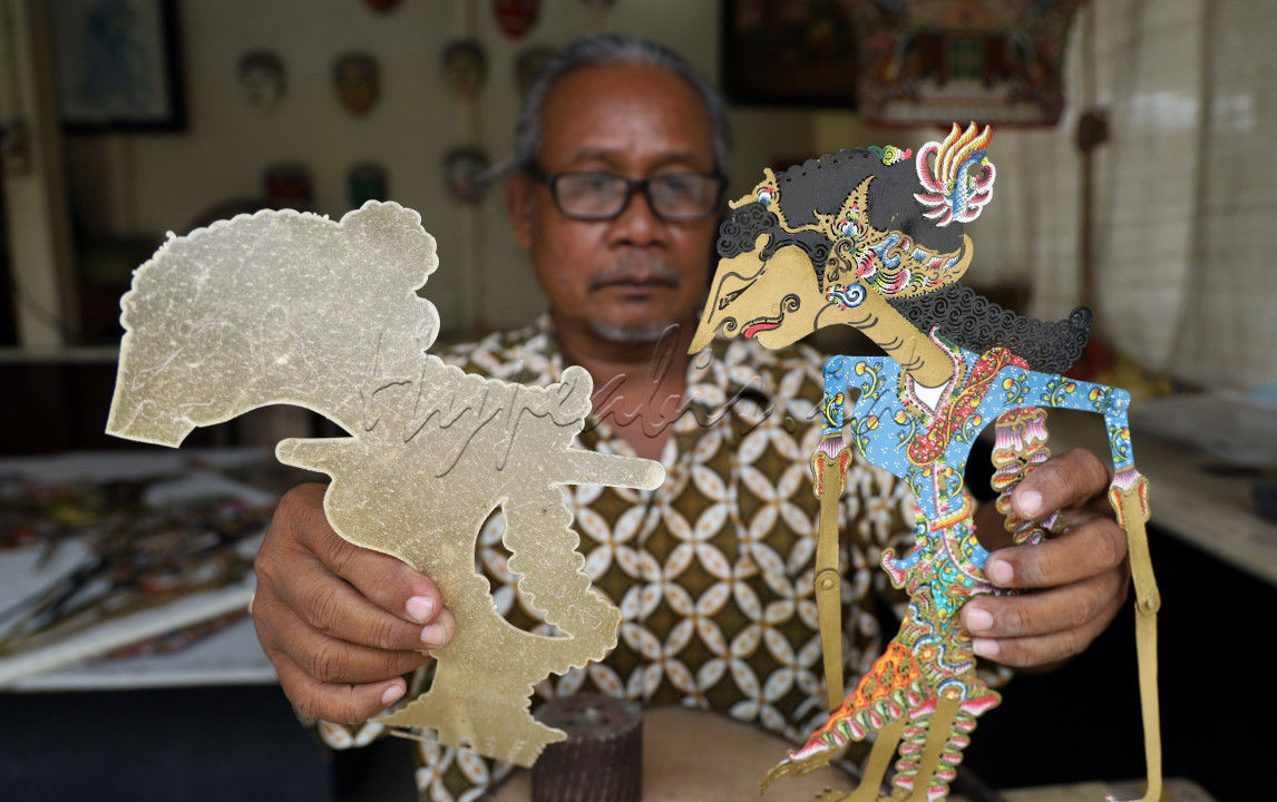 Pak Suroso, seorang pembuat wayang kulit, sedang menunjukkan wayang Dewi Kamaratih di Workshop, Museum Sonobudoyo Yogyakarta. Sebelah kiri adalah wayang Dewi Kamaratih yang belum jadi, masih berupa sketsa bahan kulit lembu yang sudah mulai terlihat bentuknya tetapi belum <em>ditatah</em> (dipahat) dan <em>disungging</em> (diwarnai). Sebelah kanan adalah wayang Dewi Kamaratih yang sudah jadi. Untuk membuat satu wayang kulit bisa memakan waktu lebih dari dua minggu.