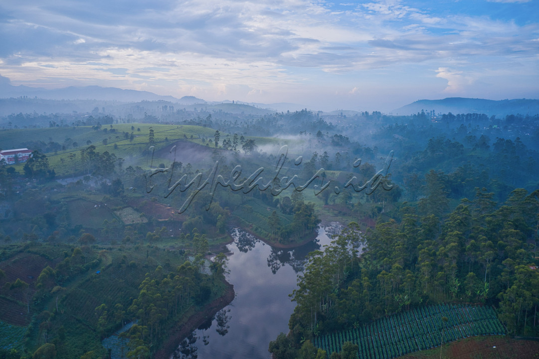Foto pemandangan alam indonesia yang indah dengan bukit bukit nya yang masih di selimuti oleh kabut.