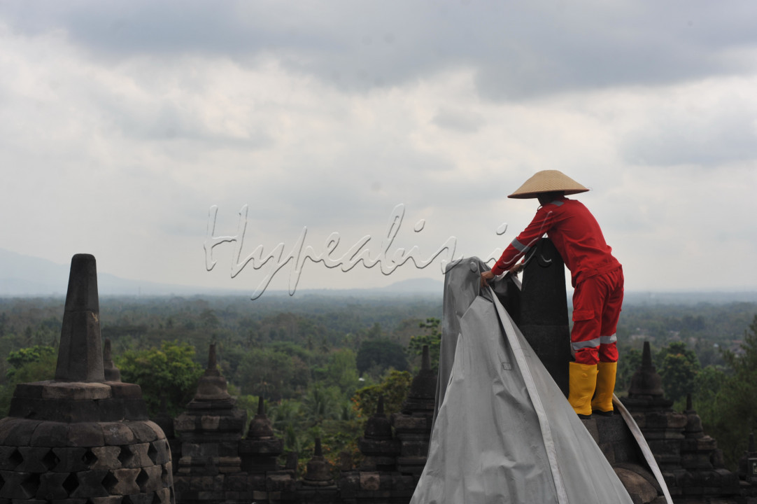 Pekerja sibuk menutupi stupa di Kawasan Candi Borobudur , Kabupaten Magelang . &nbsp;Sebanyak 73 stupa candi ditutupi terpal akibat aktifitas Gunung Merapi yang mengeluarkan abu vulkanik. &nbsp; Candi Borobudur yang merupakan warisan budaya dunia mempunyai sistem manajemen pengelolaan bencana, diatur oleh Badan Penyelidikan dan Pengembangan Teknologi Kebencanaan Geologi (BPPTKG) Yogyakarta.
