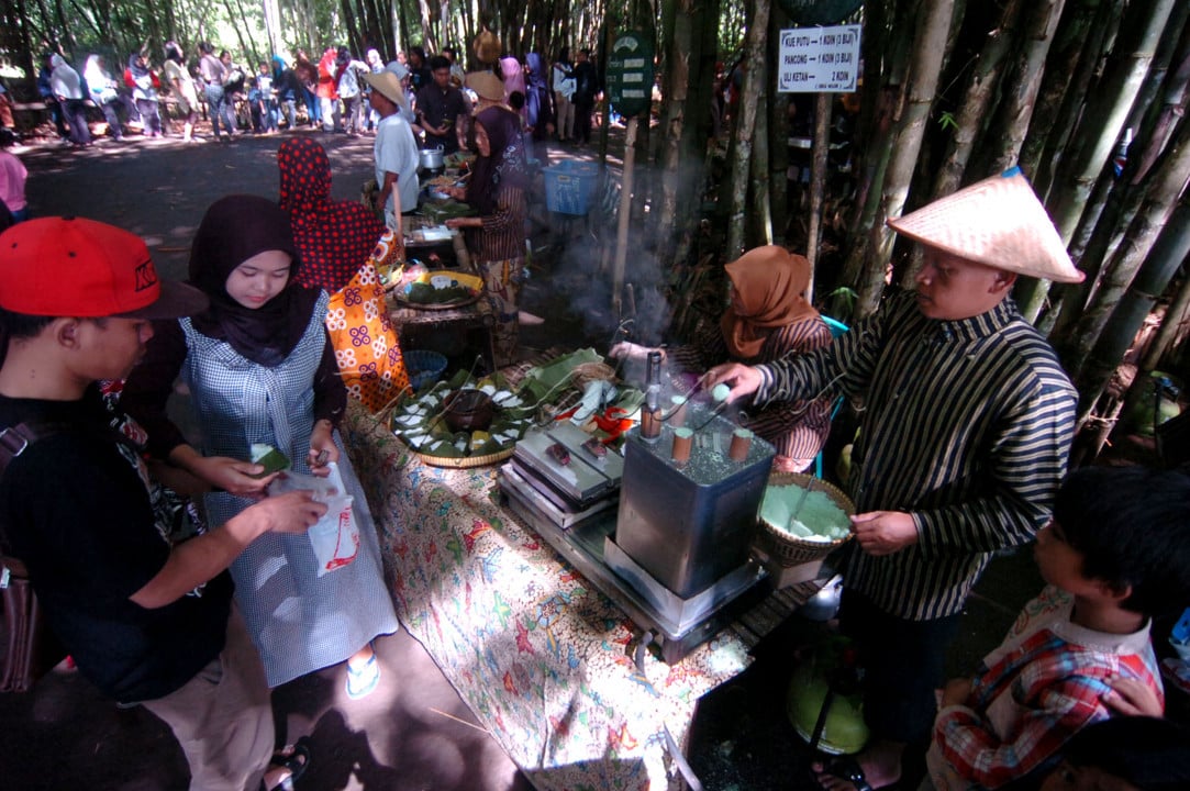 Sejumlah pengunjung membeli makanan tradisional di bawah pohon bambu di desa wisata Pasar Slumpring, Desa Cempaka, Kabupaten Tegal, Jawa Tengah. Pasar Slumpring khas dengan tanaman pring (bambu) yang hanya buka setaip hari Minggu pada pukul 07.00-12.00 WIB dengan 40 pedagang makanan dan minuman tradisional tersebut menggunakan model transaksi tidak memakai uang, tetapi menggunakan koin yang terbuat dari bambu yang ditukarkan pengunjung dengan harga Rp2.500 per koin.