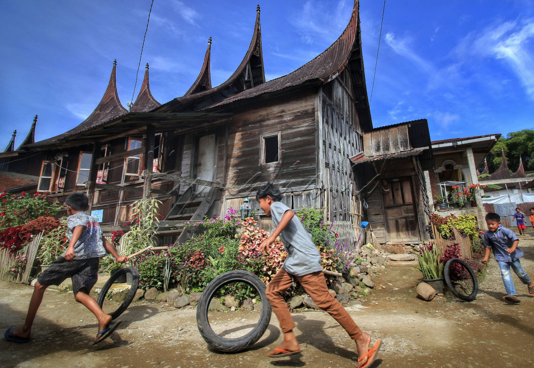 Sejumlah anak bermain ban bekas di halaman rumah gadang Minangkabau di Limapuluhkota, Sumatra Barat. Permainan tradisional itu masih dimainkan anak-anak setempat&nbsp; di tengah banjirnya permainan online. Mereka tetap memainkan permainan itu sebagai upaya rasa bangga mereka terhadap permainan anak desa di Indonesia