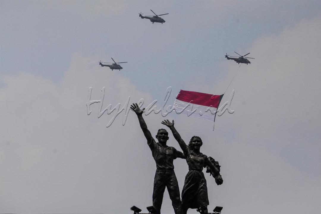 Tiga helikopter TNI AU terbang melintas sambil mengibarkan bendera merah putih saat Upacara Peringatan Detik-Detik Proklamasi di kawasan Bunderan HI, Jakarta, Selasa (17/8/2021). Sebanyak enam helikopter TNI AU mengibarkan bendera merah putih berukuran 20 x 30 meter dalam rangka memperingati HUT kemerdekaan ke-76 RI.&nbsp;