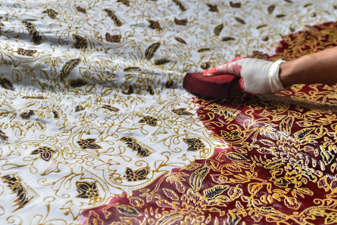 Pekerja melakukan pewarnaan batik cetak di rumah produksi batik tanah liek di Padang, Sumatera Barat.&nbsp;