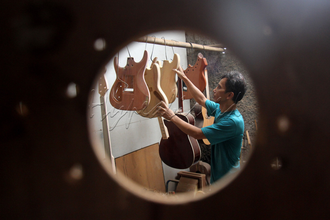 Perajin beraktivitas menyelesaikan pembuatan gitar di sentra produksi berskala rumahan