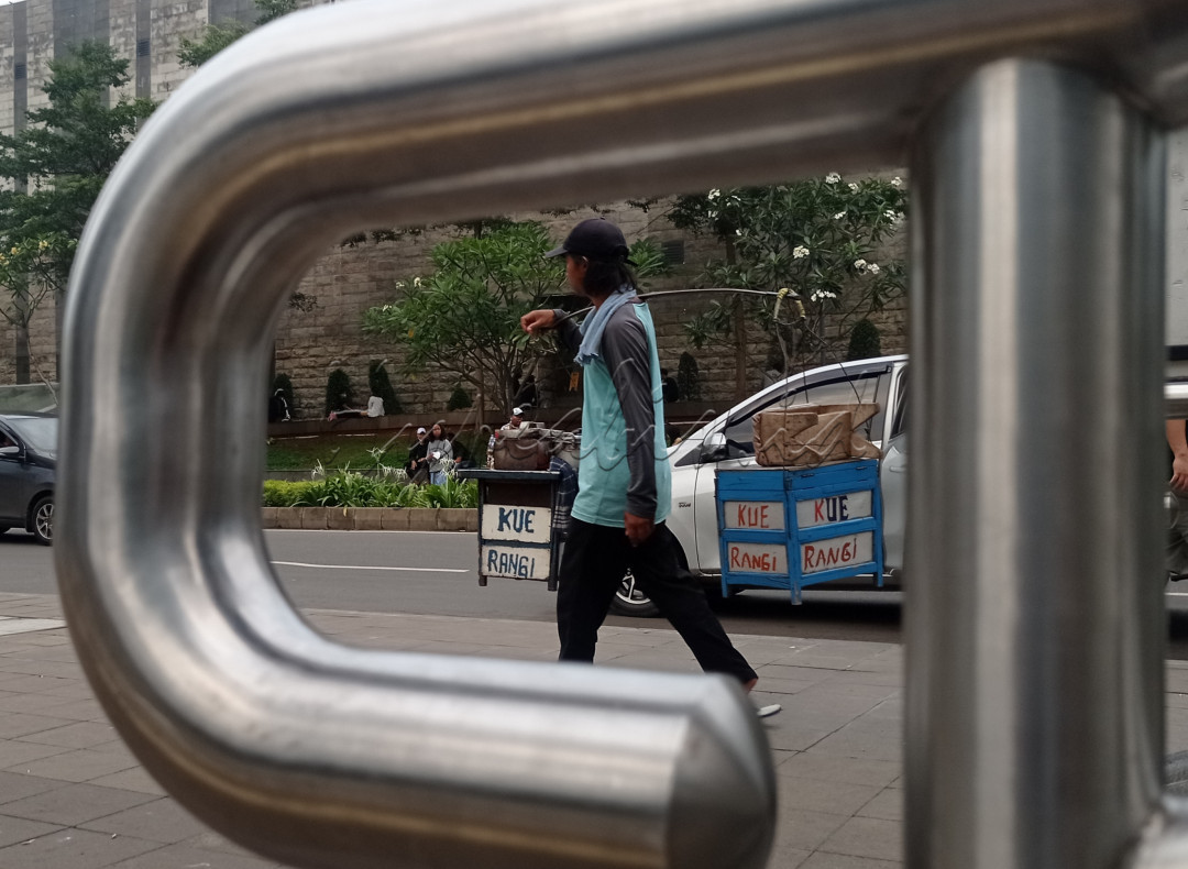Pedagang kue sedang berkeliling di jalan Sudirman.&nbsp;