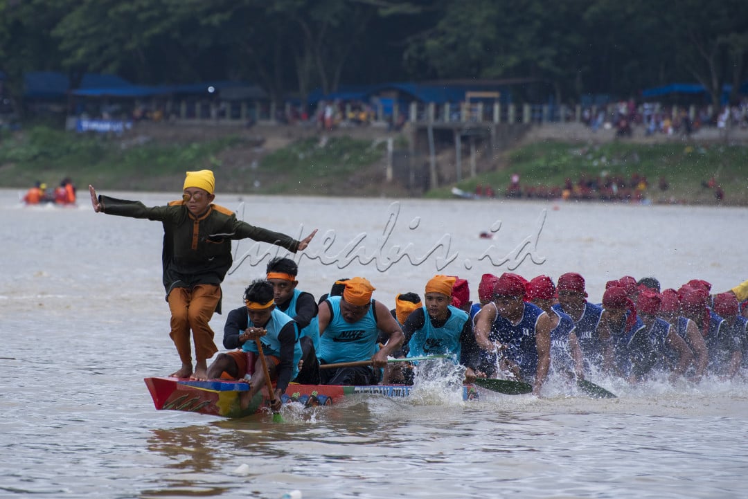 Seorang anak berdiri sambil menari berada di atas sampan untuk memberikan semangat kepada para pedayung dalan Iven lomba Pacu jalur yang di selenggarakan di Kabupaten Kuantan Singingi Provinsi Riau&nbsp;