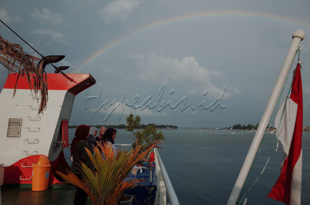 beberapa orang wisatawan domestik menikmati pagi bersama pelangi di atas dek kapal ferry Siginjai sebelum pulang meninggalkan pulau Karimunjawa. kapal penyebrangan ferry Siginjai merupakan salah satu transportasi yang bisa dipilih wisatawan untuk pulang dan pergi ke Taman Nasional Karimunjawa dengan estimasi waktu tempuh 4-5 jam perjalanan.<br />
<br />
lokasi: Pelabuhan Karimunjawa, Jawa Tengah