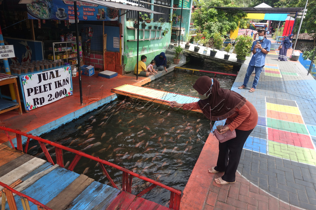 Pengunjung wisata Ikan Kali Gajah Wong, Yogyakarta, Senin (28/2/2022).<br />
Memberi makan ikan, makanan ikan dijual pengelola sekitar RP 2000 saja.