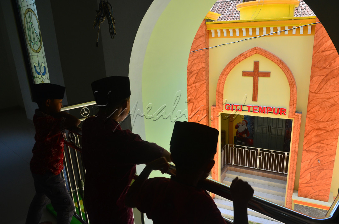 Sejumlah anak berada di dalam Masjid Nurul Hikmah yang berhadapan dengan Gereja Injil Tanah Jawa (GITJ) di Dukuh Pekoso, Desa Tempur, Keling, Jepara, Jawa Tengah, Jumat (15/4/2022). Meski masjid dan gereja tersebut saling berhadapan, warga setempat tetap menjalankan ibadah tanpa saling mengganggu serta hidup rukun dan saling menghargai