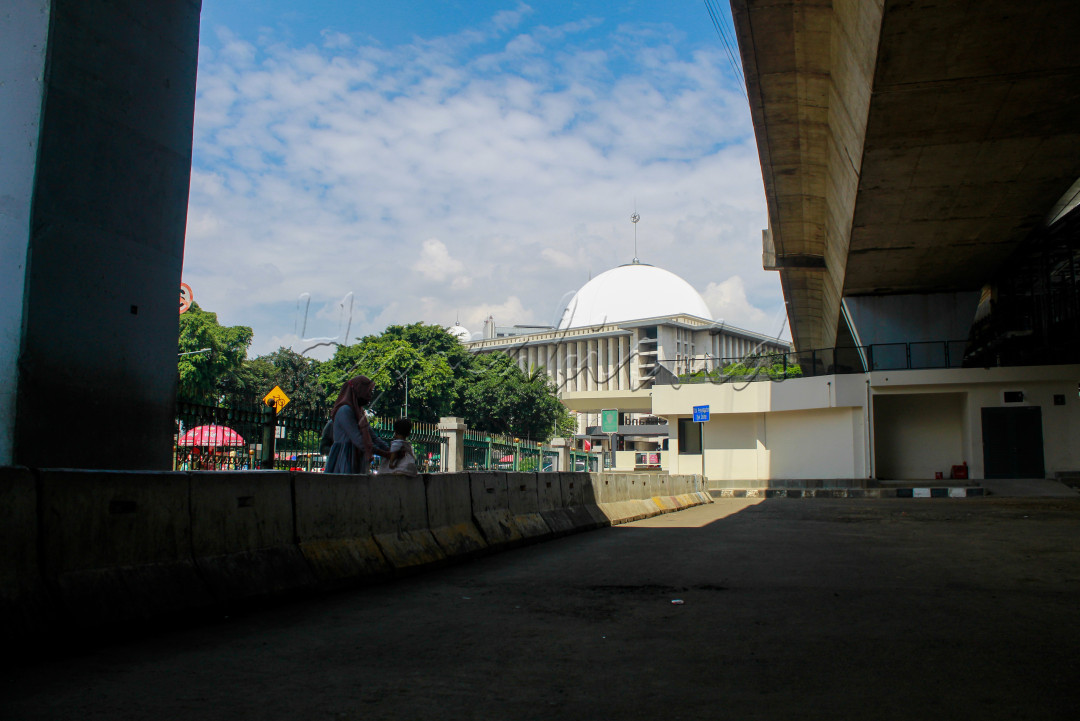 Seorang ibu bersama anaknya berada di bawah flyover Stasiun Juanda, Jakarta Pusat. Dari tempat mereka berdiri terlihat mesjid Istiqlal.
