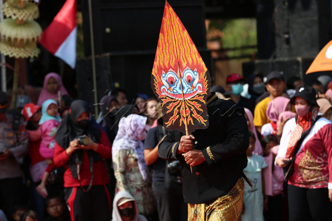 MEMBAWA GUNUNGAN: Seorang peserta Karnaval Pembangunan yang memerankan karakter seorang Dalang, berjalan menuju panggung utama sambil membawa Gunungan Wayang untuk melaporkan keberangkatan rombongannya.<br />
<br />
Pemerintah Kota Mojokerto, Jawa Timur, menggelar Karnaval Pembangunan pada hari Sabtu, 26 Agustus 2023 dalam memeriahkan HUT Kemerdekaan Indonesia ke-78 dengan menyajikan berbagai seni dan tarian serta kendaraan hias dari berbagai instansi pemerintah Kota Mojokerto yang berlangsung sangat meriah.<br />
<br />
Setiap tahun, Pemerintah Kota Mojokerto dalam pelaksanaan Karnaval ingin menggali potensi pariwisata melalui proses kreatif yang dituangkan dengan kendaraan hias serta gelaran berbagai seni.