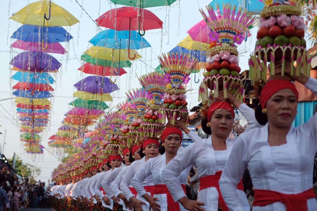 Sejumlah perempuan Bali menjunjung gebogan atau sesajen berisi buah, kue, bunga dan hiasan janur saat Tradisi Mapeed di Tanah Lot, Tabanan, Bali, Sabtu (24/6/2023).